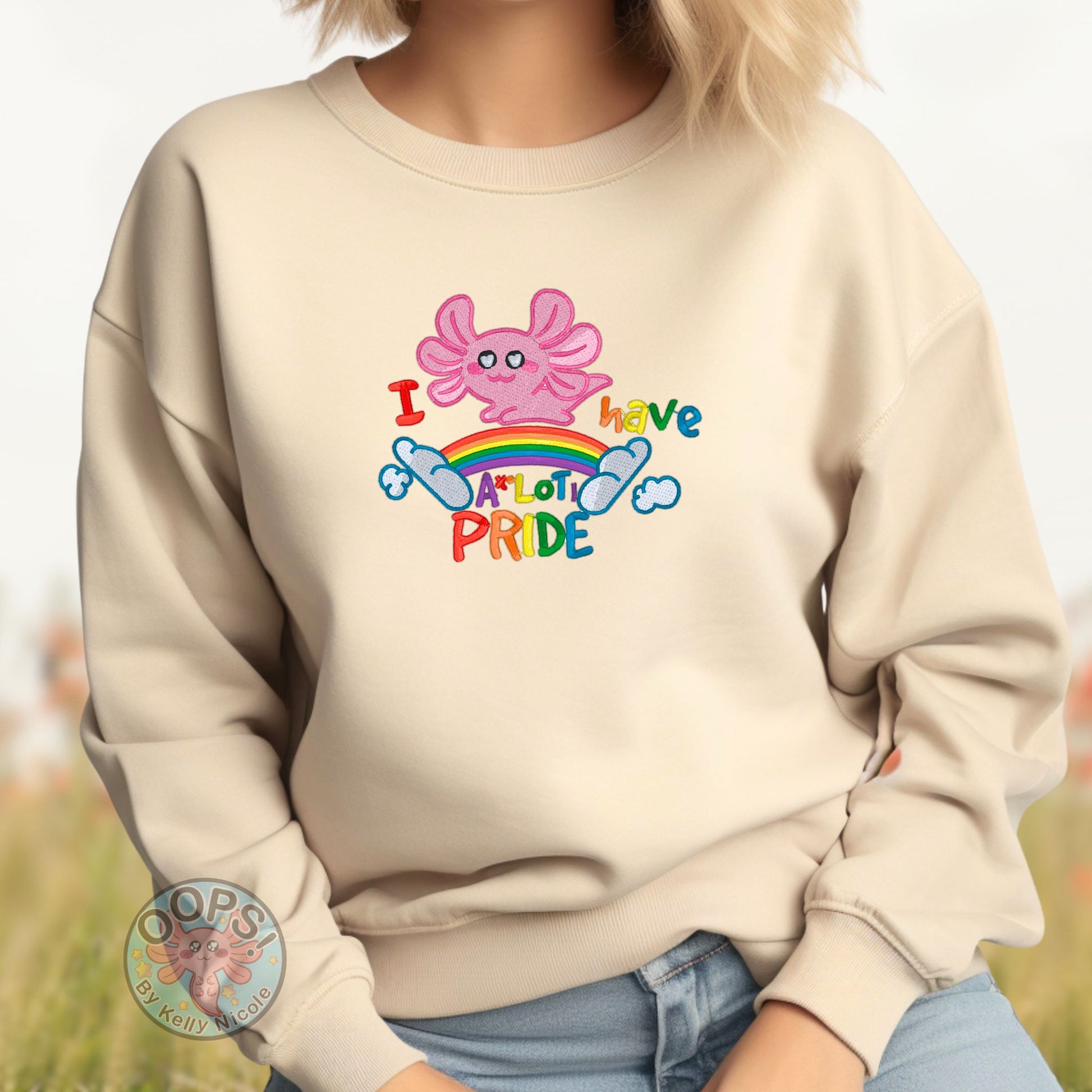 Embroidered "Axolotl PRIDE" Rainbow LGBTQIA+ Unisex Custom Sweatshirt in Sand. Order yours today at https://oopsbykellynicole.com.