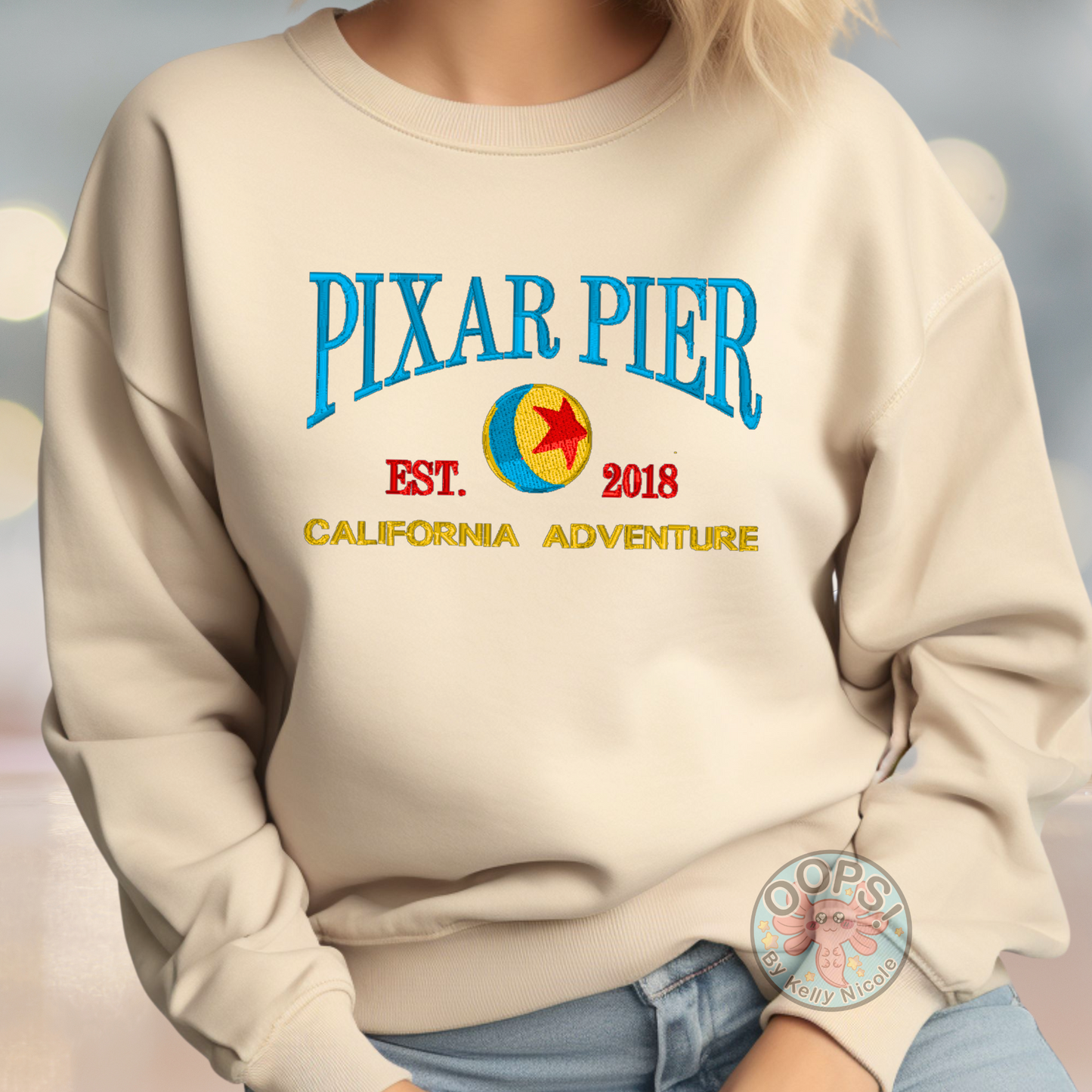 Embroidered Disney “Pixar Pier” DCA inspired  Unisex  Sweatshirt in Sand. Perfect for Home, work or anytime cozy comfort wear.  Order yours today at https://oopsbykellynicole.com.