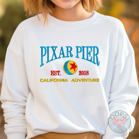 Embroidered Disney “Pixar Pier” DCA inspired  Unisex  Sweatshirt in White. Perfect for Home, work or anytime cozy comfort wear.  Order yours today at https://oopsbykellynicole.com